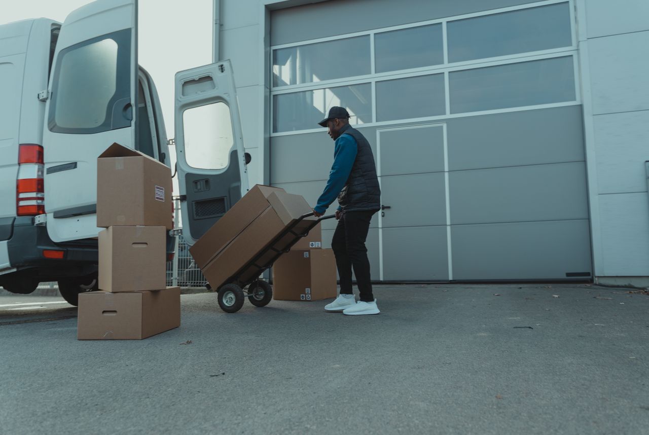 Courier unloading packages from a delivery van at a warehouse entrance. Efficient distribution.